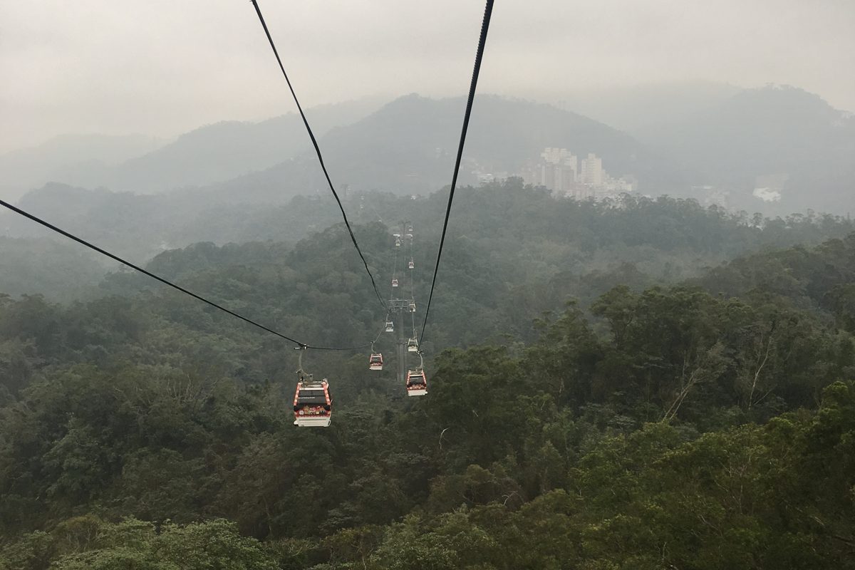 Cable cars over forested hills near Taipei in low cloud